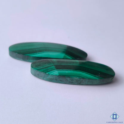 cabochons4sale, green malachite oval cabochons featuring swirling natural patterns, deep emerald tones and distinctive gemstone character held between fingers