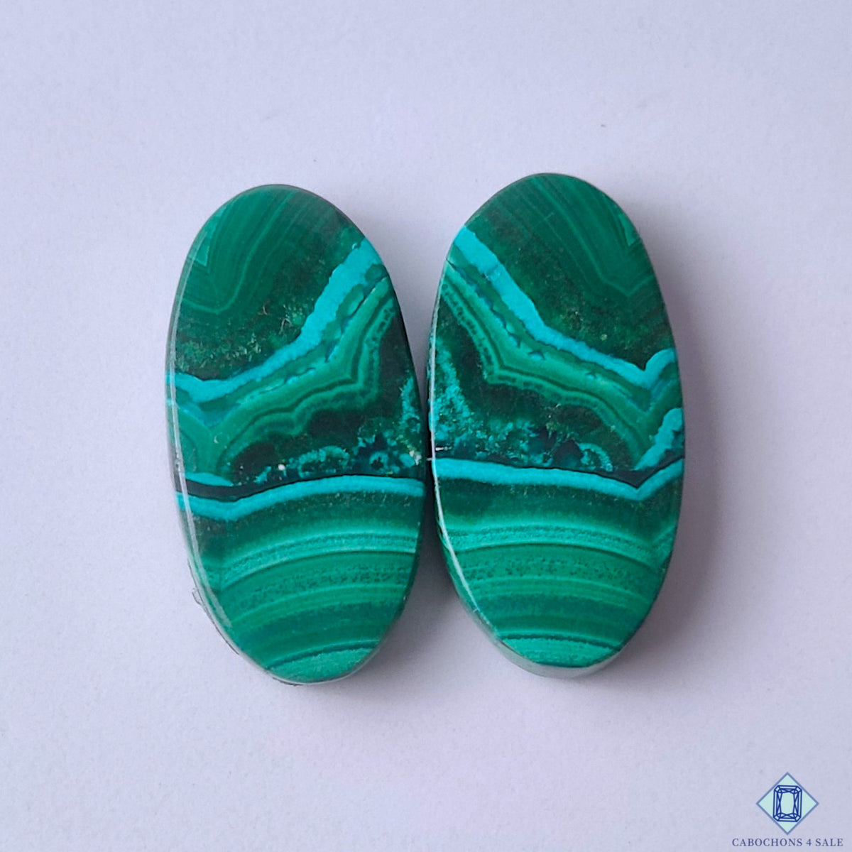 cabochons4sale, rich green malachite oval cabochons with layered concentric bands and natural mineral depth held between fingers