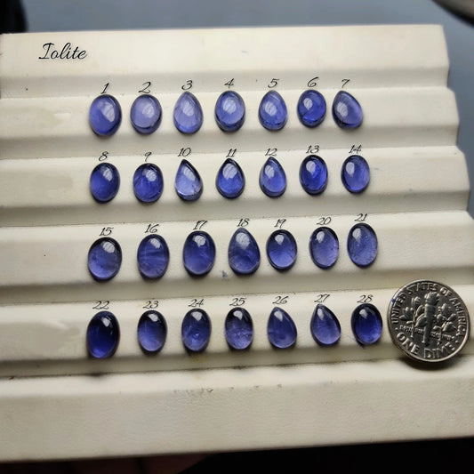 Cabochons4sale collection of natural blue-violet iolite cabochon gemstones in oval and teardrop shapes on a display tray.