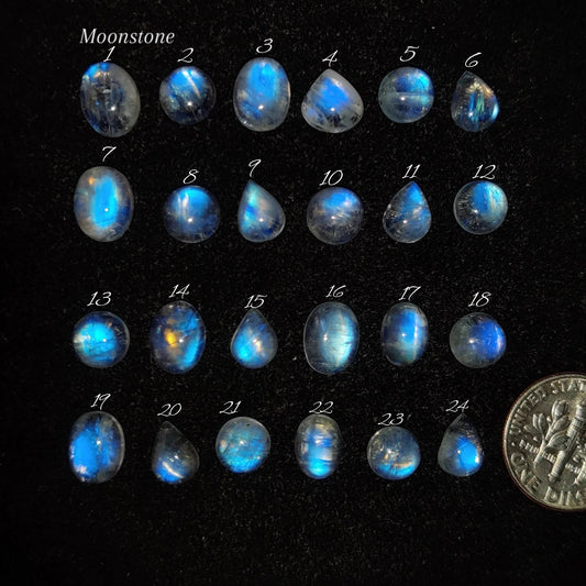 Cabochons4sale collection of 24 polished natural moonstone cabochons with ethereal blue adularescence on black velvet.