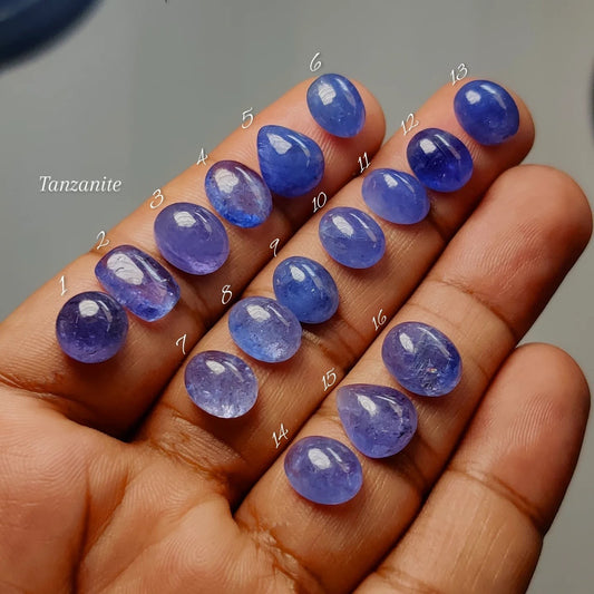 Cabochons4sale natural blue-violet tanzanite cabochons in various shapes and sizes held in a hand for jewelry making.