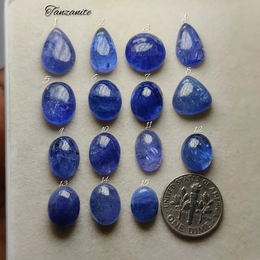 Cabochons4sale collection of natural blue-violet tanzanite cabochons in various shapes and sizes next to a US dime.