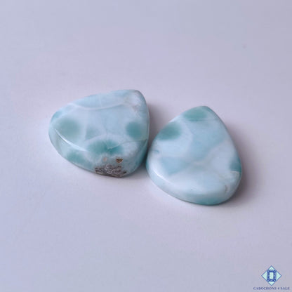 cabochons4sale, ocean-inspired larimar pear cabochons in blue and white shades featuring flowing mineral designs, natural texture and artisan polish held between fingers