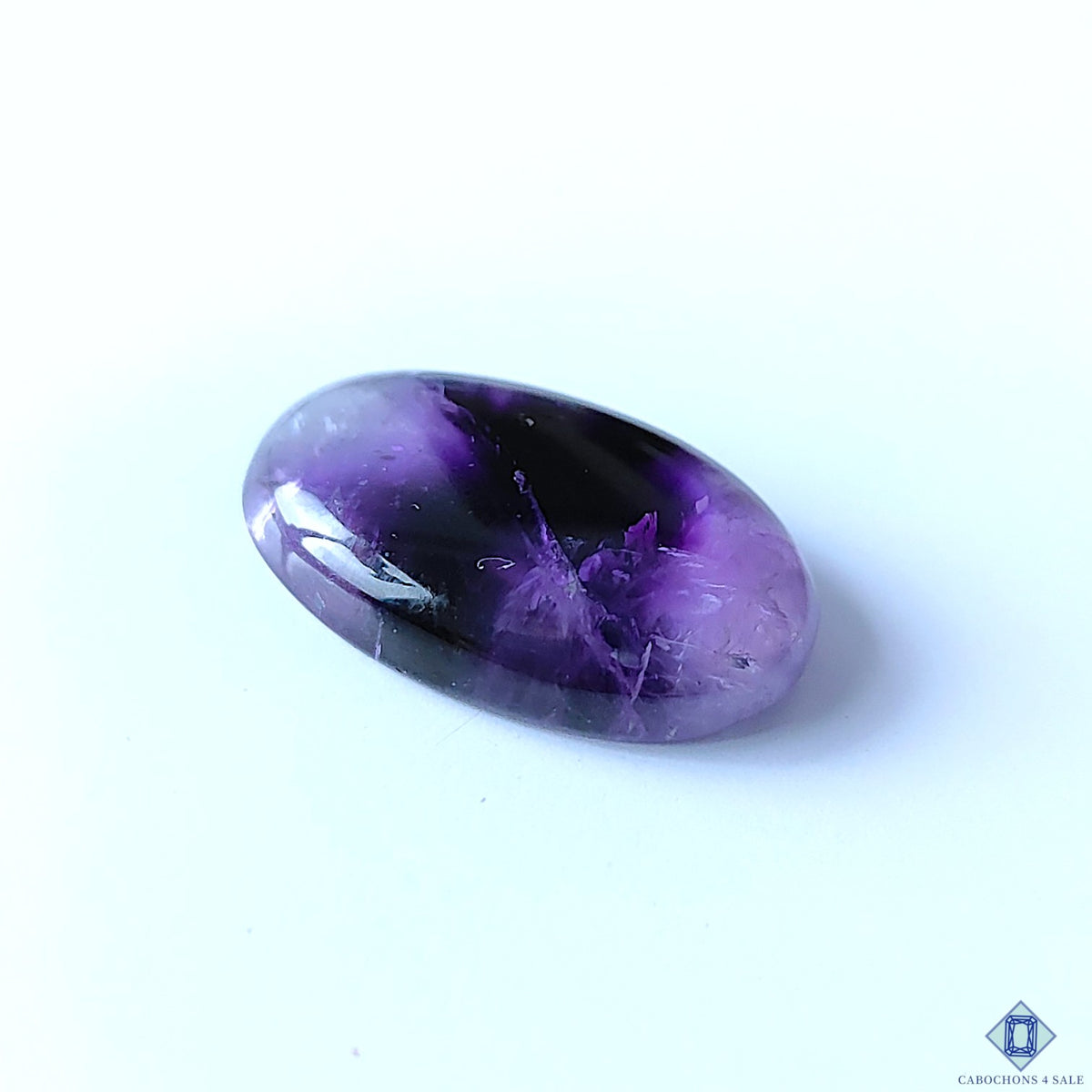 cabochons4sale, polished trapiche amethyst oval cabochons featuring vivid purple coloration, star-like internal patterns and distinctive natural gemstone character held between fingers