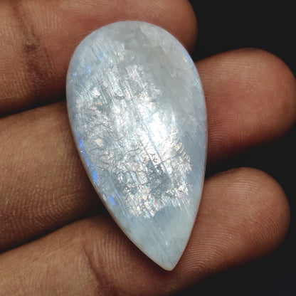 Cabochons4sale pear-shaped translucent white moonstone cabochon held in fingers showing iridescent shimmer
