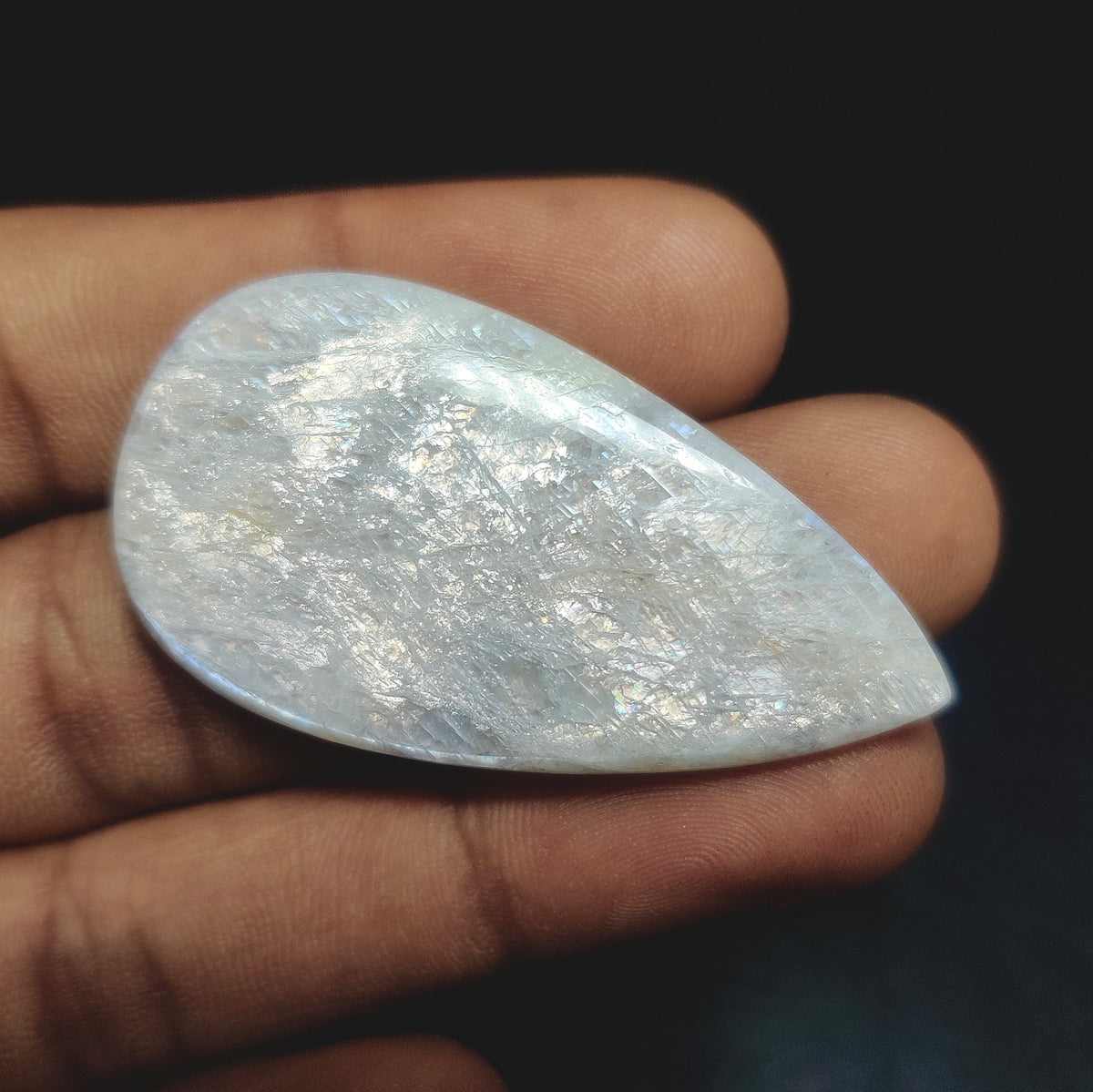 Cabochons4sale pear-shaped translucent white moonstone cabochon held in hand showing iridescent shimmer