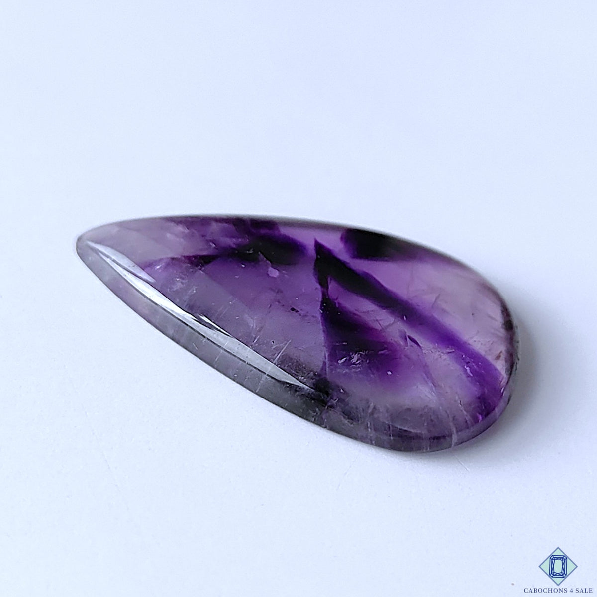 cabochons4sale, polished trapiche amethyst pear cabochons showcasing vivid violet coloration, star-like internal zoning and distinctive natural gemstone character held between fingers