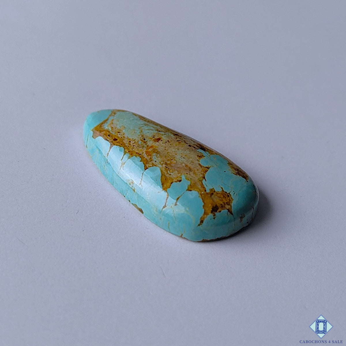 cabochons4sale, polished turquoise pear cabochons showcasing vibrant blue color with golden yellow accents, organic matrix details and unique natural stone character held between fingers