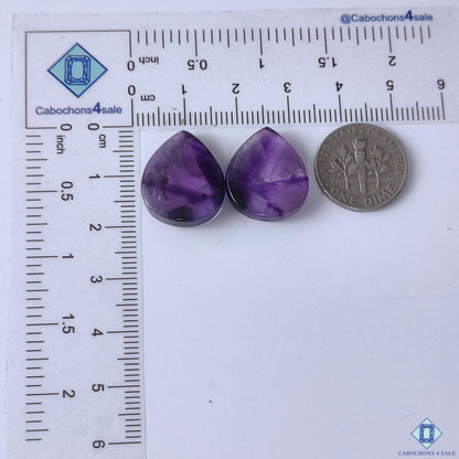 cabochons4sale, deep purple amethyst pear gemstone cabochons showcasing luminous violet tones, natural mineral character and a smooth polished finish held between fingers