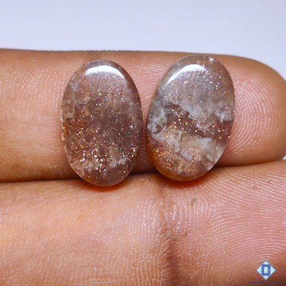 cabochons4sale, purple haze sunstone oval cabochons in rich purple tones with subtle shimmering reflections and smooth polished gemstone surfaces held between fingers