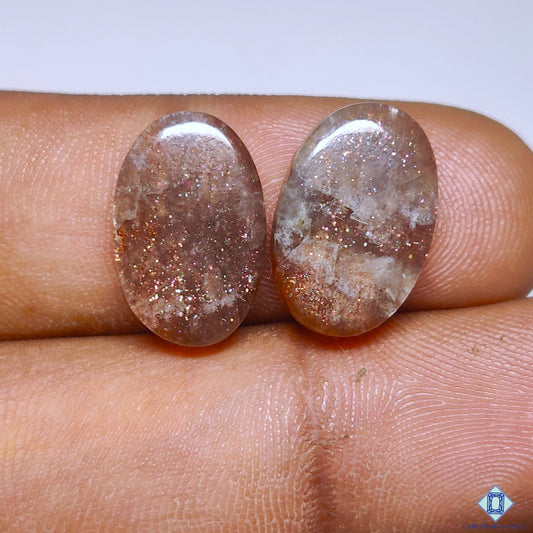 cabochons4sale, purple haze sunstone oval cabochons in rich purple tones with subtle shimmering reflections and smooth polished gemstone surfaces held between fingers