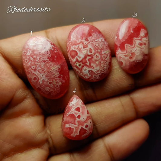 Cabochons4sale natural rhodochrosite cabochons with vibrant pink and white lace-like banding held in a hand.