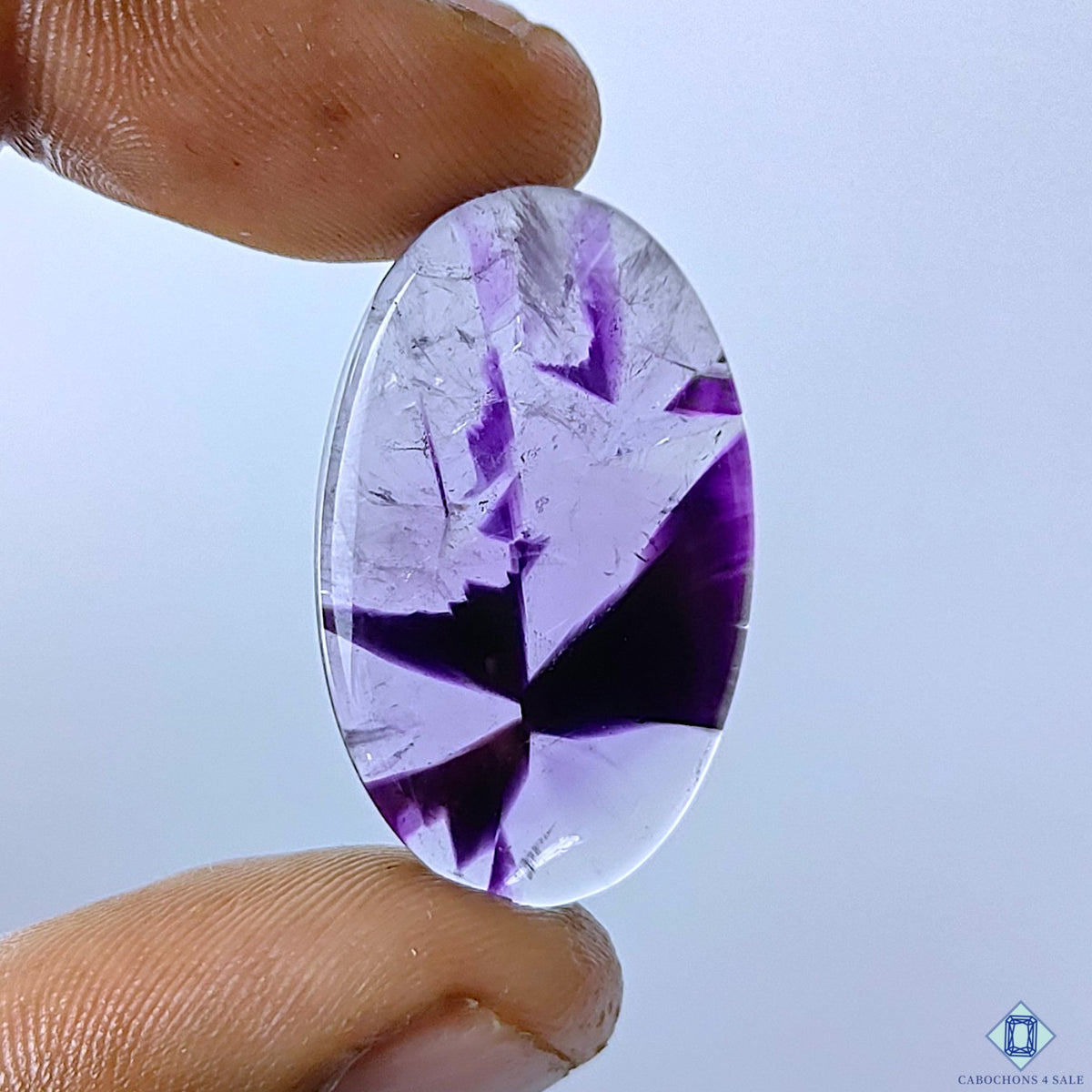 cabochons4sale, trapiche amethyst oval cabochons in deep purple shades with striking radial patterns, natural crystal zoning and a smooth polished finish held between fingers
