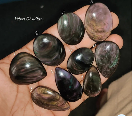 Cabochons4sale natural velvet obsidian gemstones in various polished shapes held in a hand for jewelry making.
