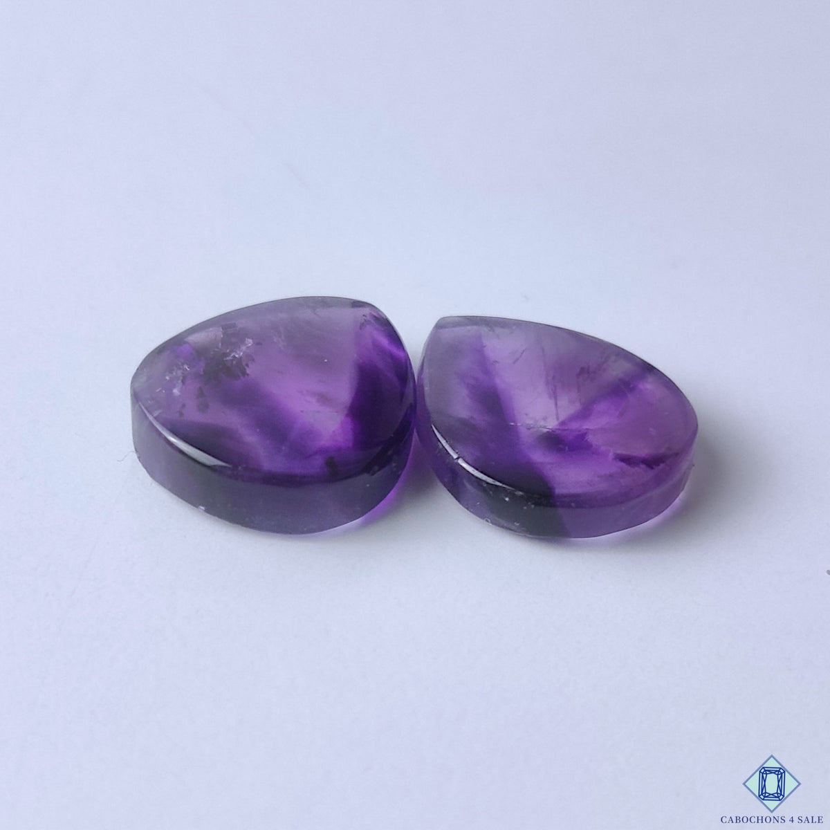 cabochons4sale, elegant violet amethyst pear cabochons featuring beautiful purple saturation, crystalline depth and artisan-polished gemstone surfaces held between fingers