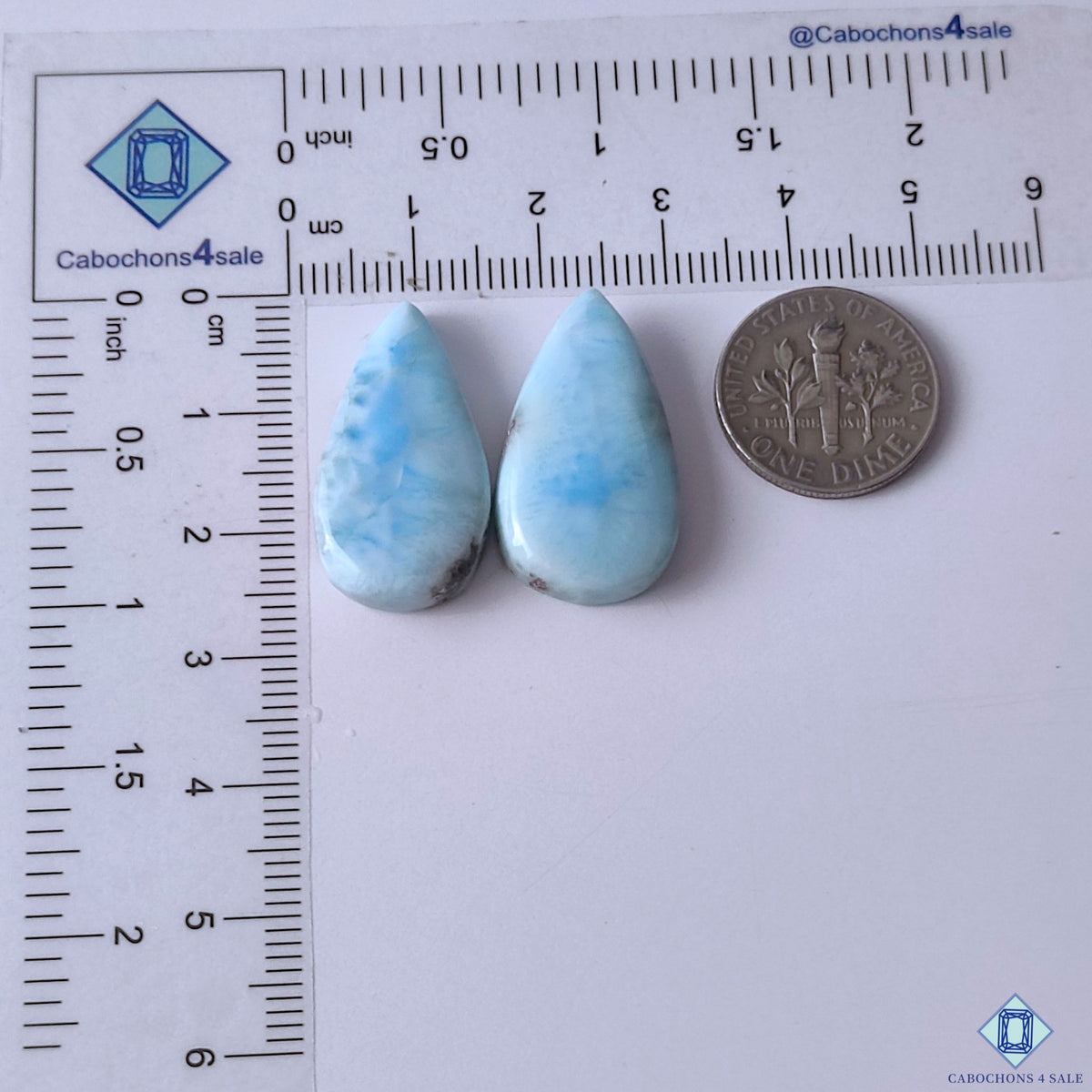 cabochons4sale, white and blue larimar pear gemstone cabochons displaying cloudy mineral formations, aqua tones and smooth polished surfaces held between fingers