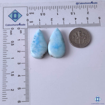 cabochons4sale, white and blue larimar pear gemstone cabochons displaying cloudy mineral formations, aqua tones and smooth polished surfaces held between fingers
