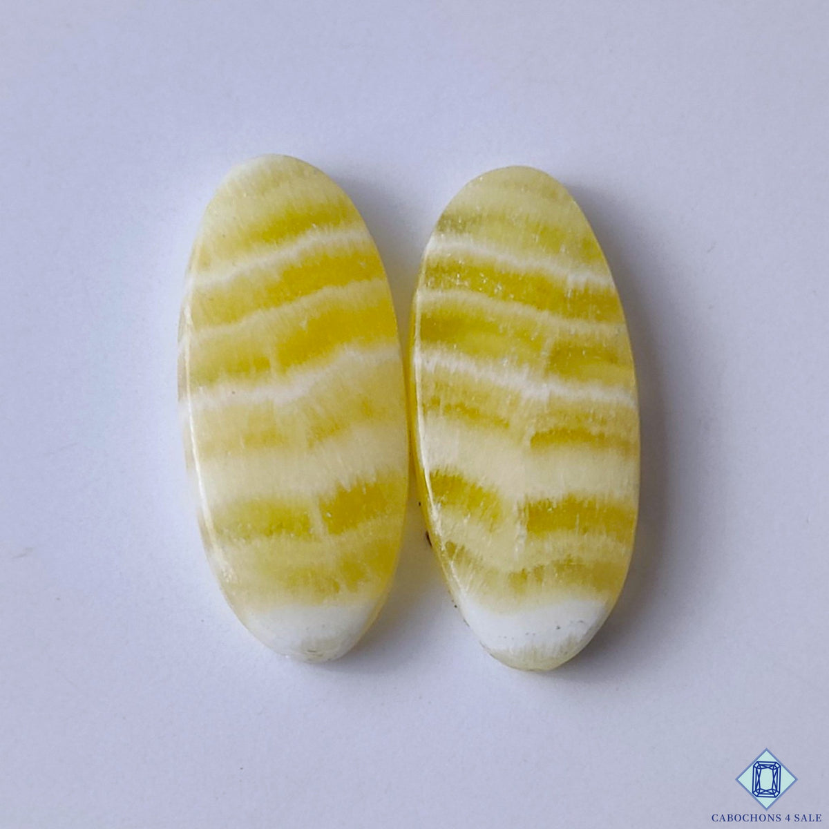 cabochons4sale, natural yellow calcite oval cabochons with warm honey tones, gentle translucency and smooth polished gemstone surfaces held between fingers