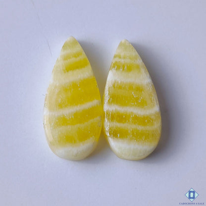 cabochons4sale, natural yellow calcite pear cabochons with warm golden tones, soft translucency and smooth gemstone polish held between fingers